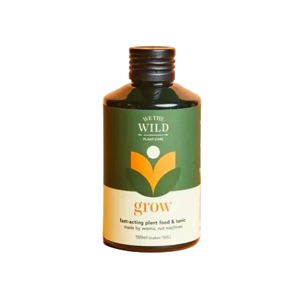 A 150ml bottle of We The Wild Plant Care 'grow' fast-acting plant food and tonic, featuring a dark green and cream label with an orange leaf logo, set against a solid peach background.